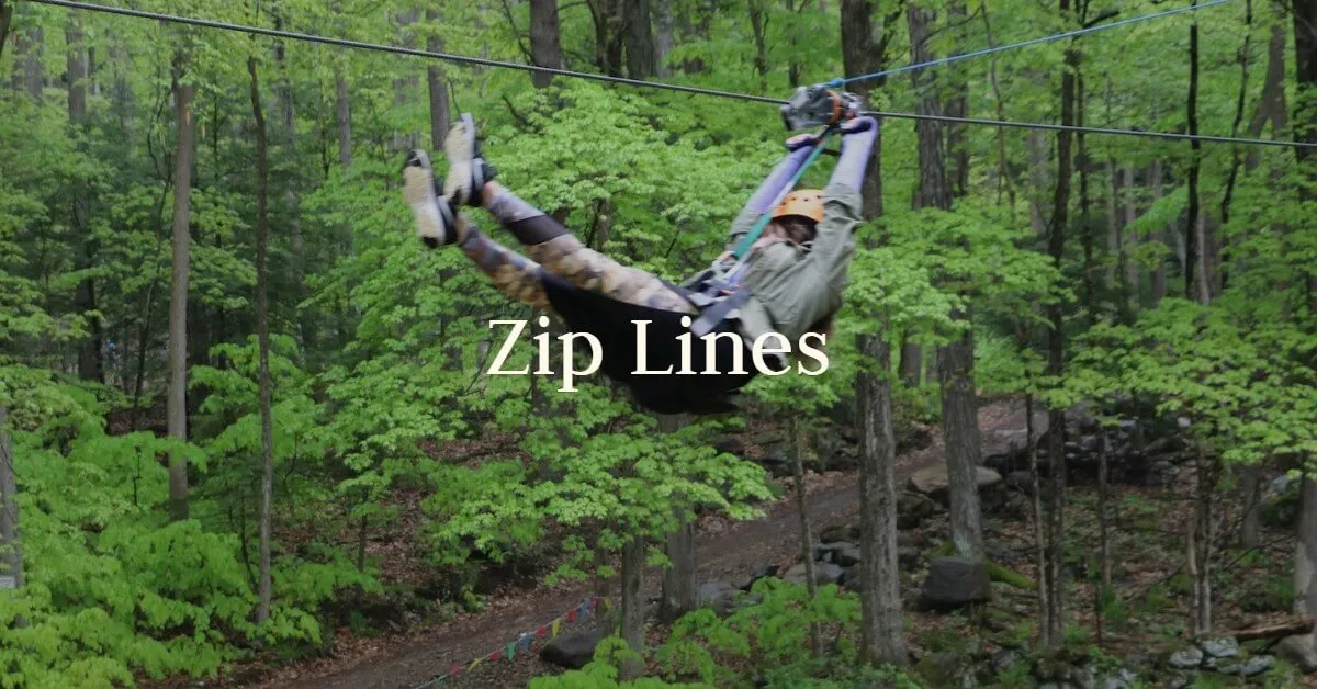 A guest flies feet-first down a zip line through the forest