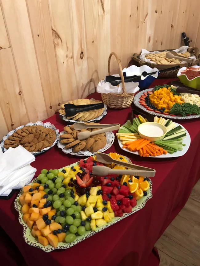 A buffet table spread with fruit platters, vegetables and dip, pastries and cookies