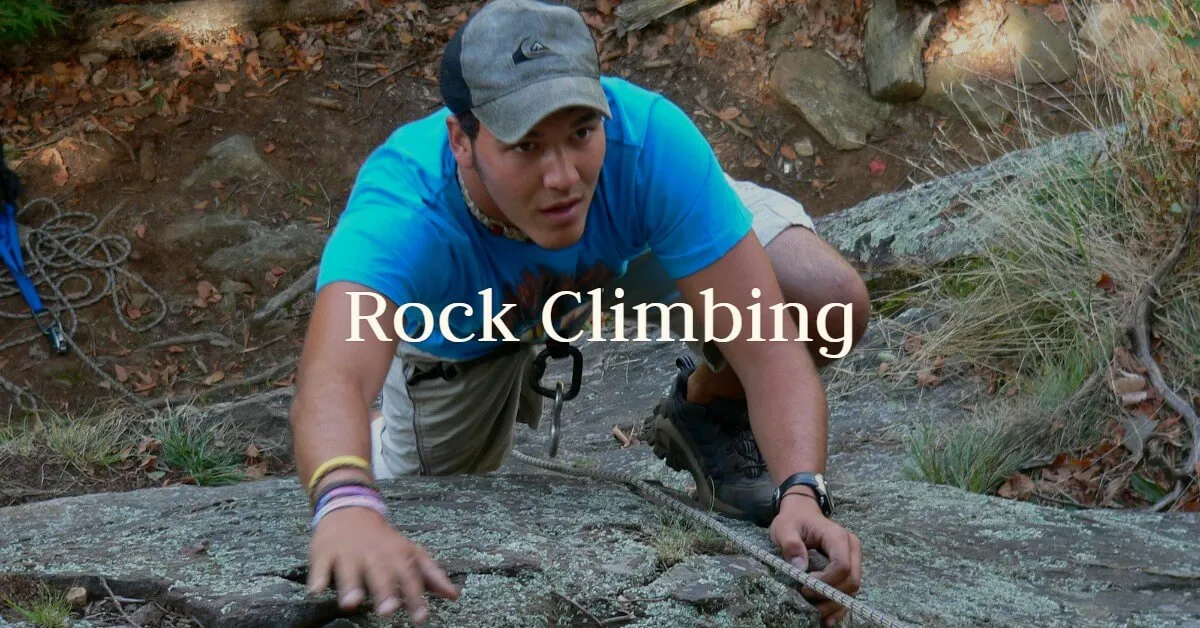 A guest in a cap climbs up a natural rock face