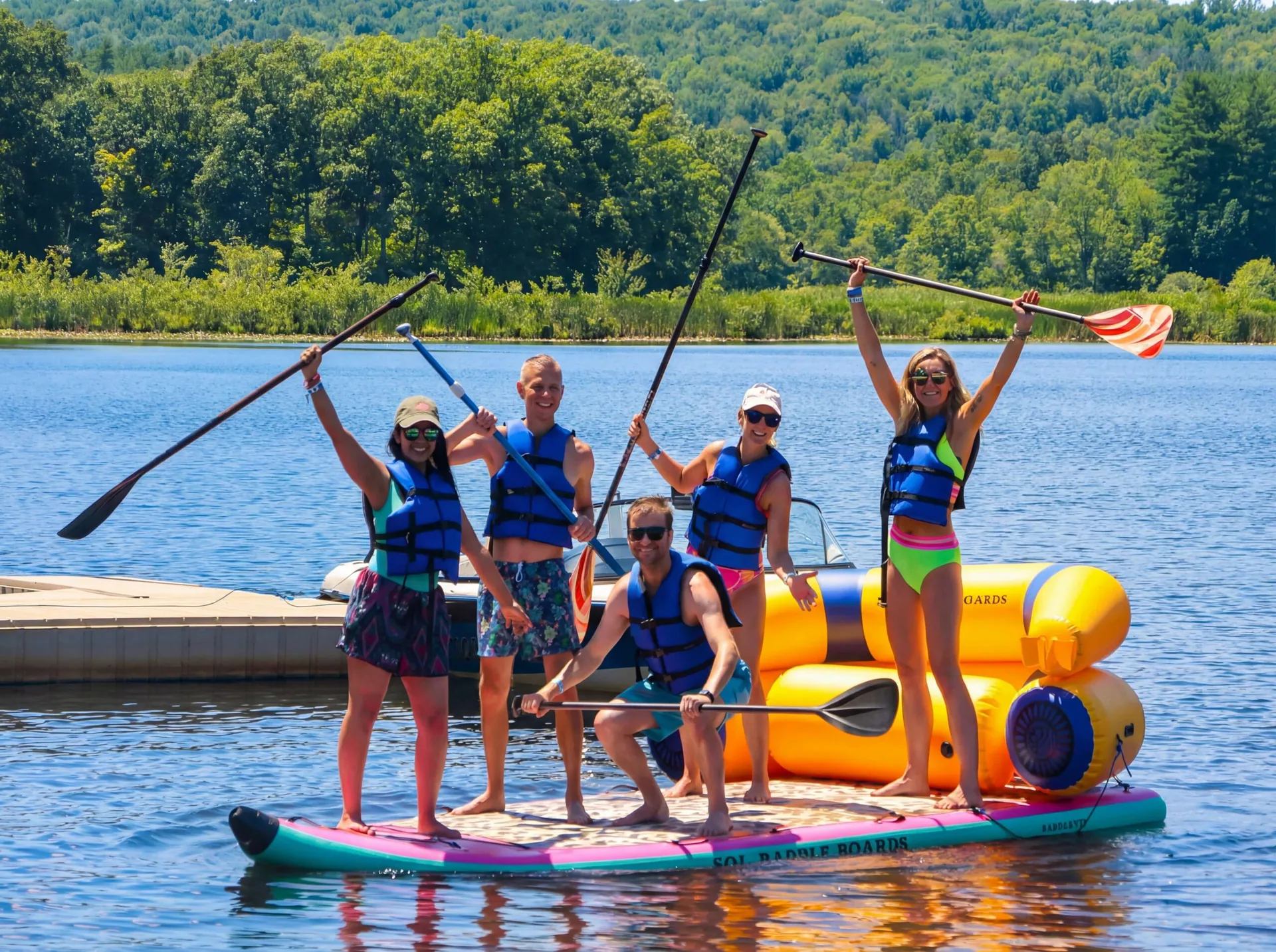 Guests in life jackets paddleboarding and playing on the lake