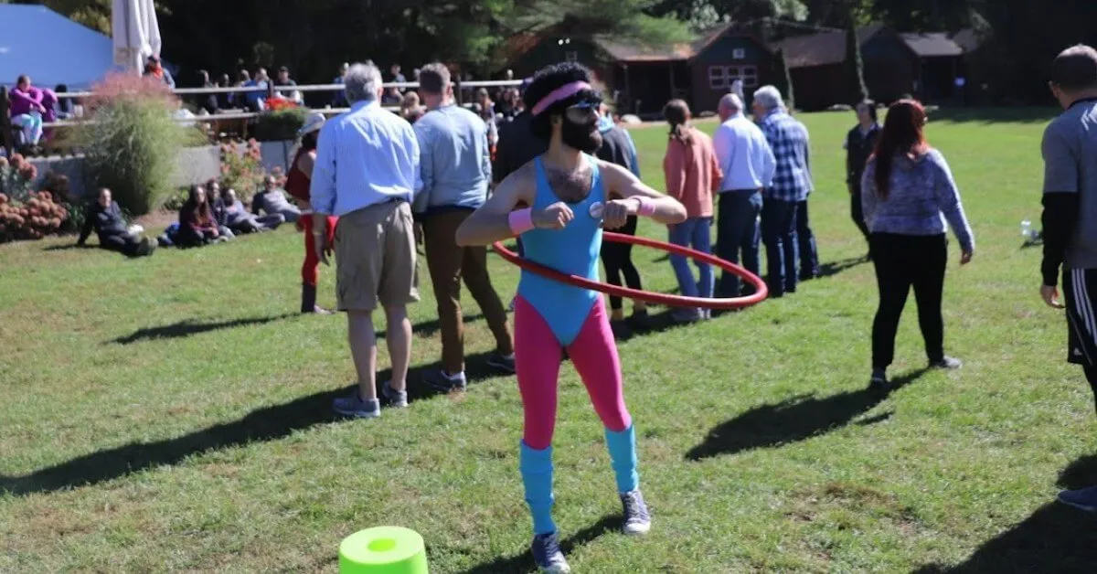A guest in neon '80s gear spins a hula hoop as a crowd watches