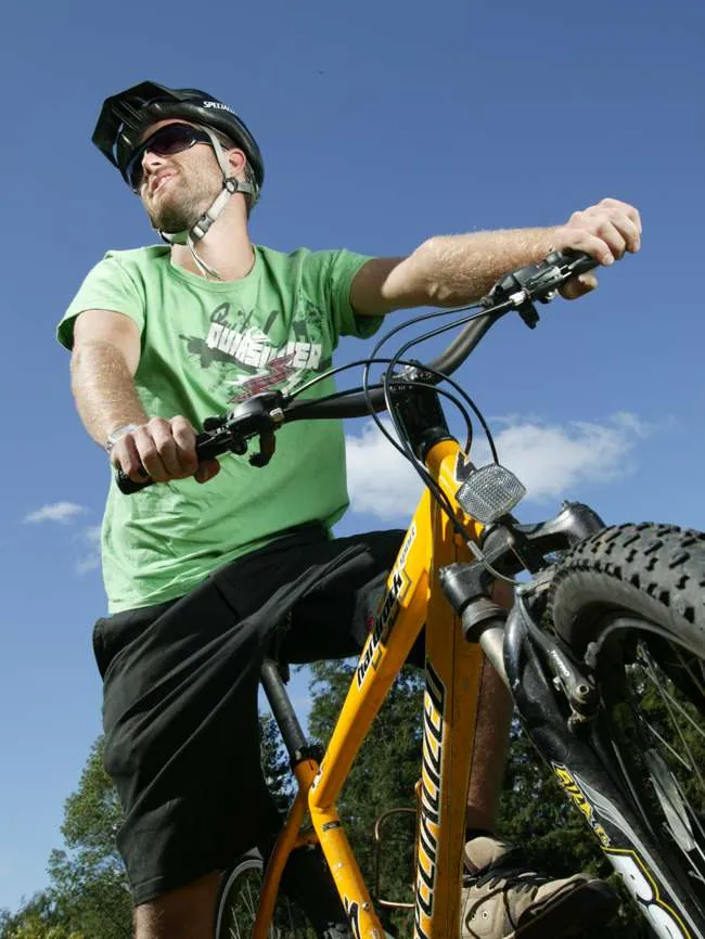 Man in a helmet and sunglasses riding a yellow fat-tire mountain bike against a blue sky