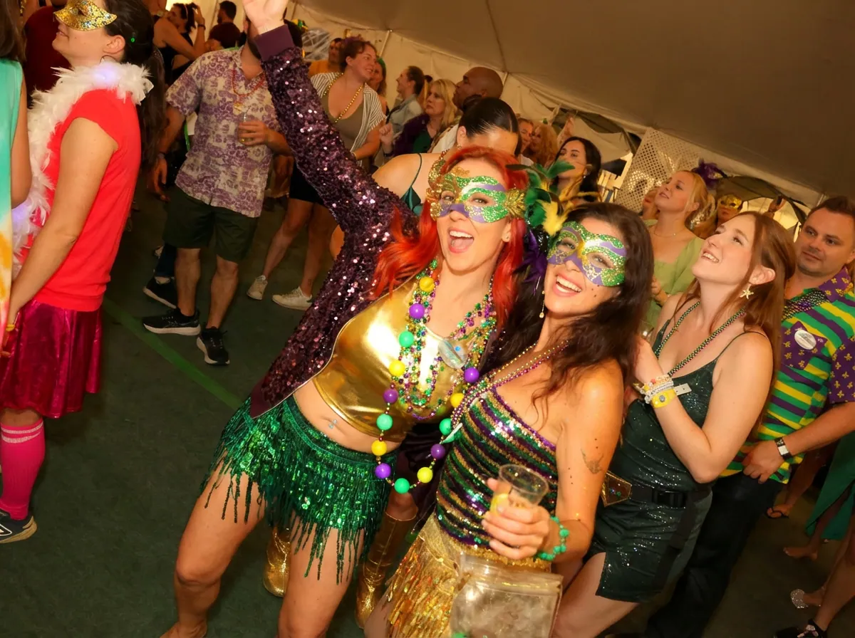 Guests in Mardi Gras masks and sequins dancing at a themed party