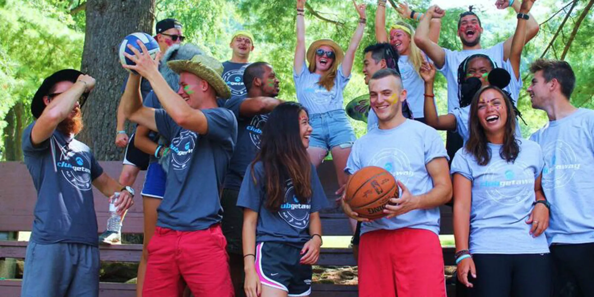 Group in matching camp T-shirts cheering on bleachers in the woods