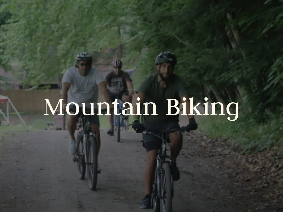 Guests ride mountain bikes down a shaded trail