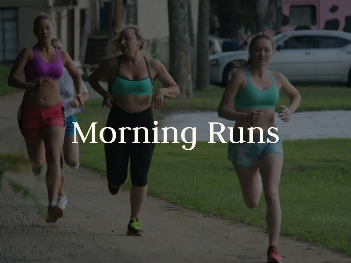 Guests jog together along a tree-lined camp road