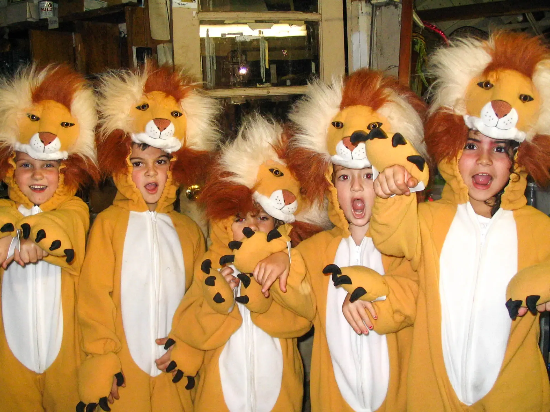 Five grinning kids in lion costumes posing with their claws out