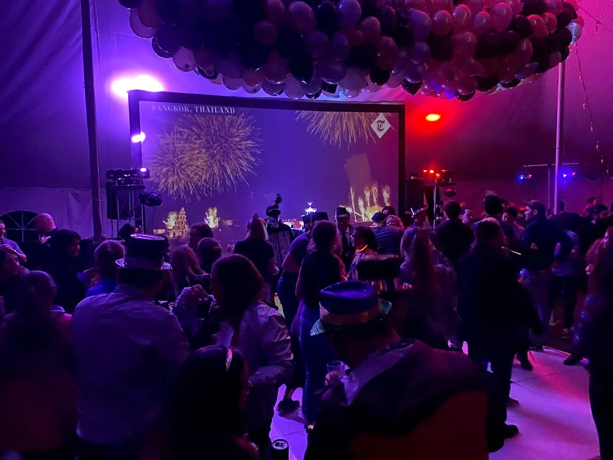 Crowd dancing under a purple-lit balloon drop at a party