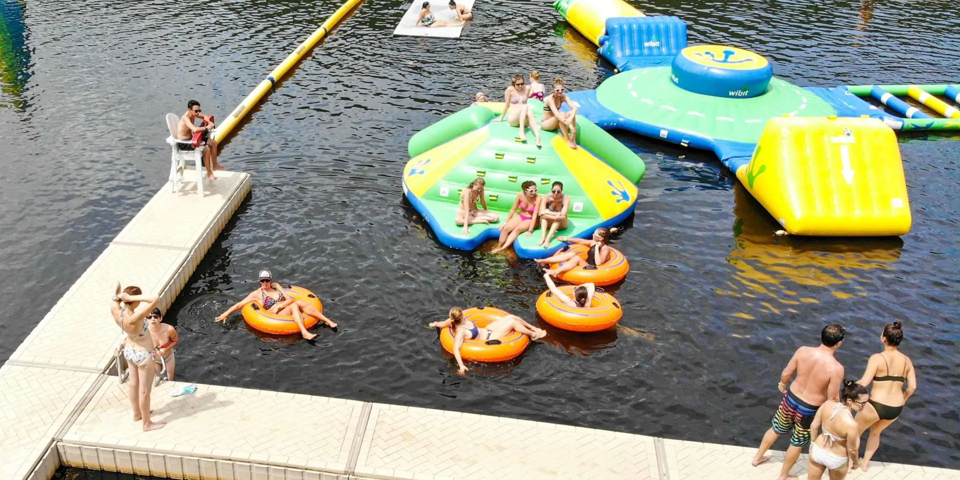 Guests floating on tubes around inflatables next to the lake dock