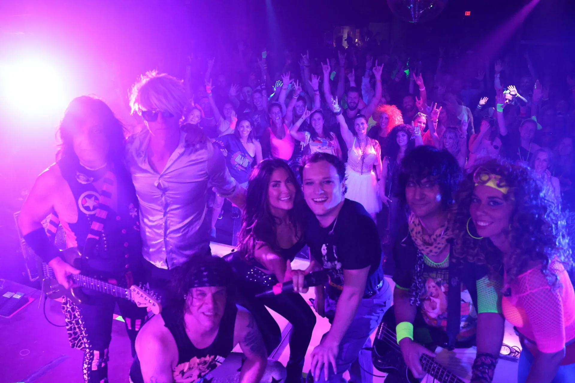 Crowd of guests in costumes partying under purple lights