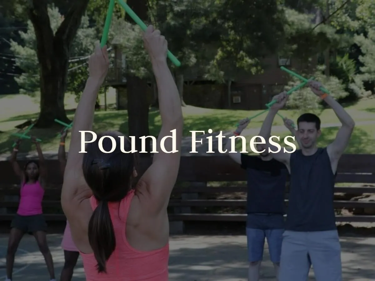 Guests raise drumsticks overhead during a Pound Fitness class