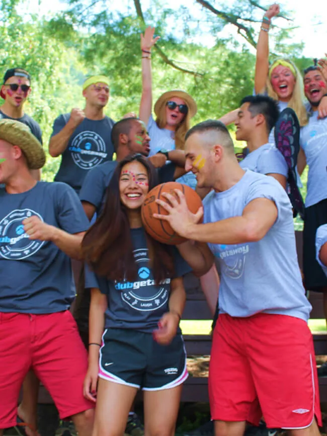 A cheering group of young people in matching T-shirts, one holding a basketball