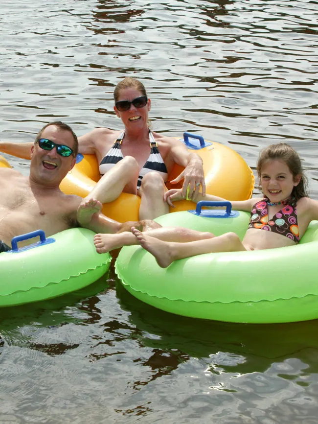 A dad, mom and daughter relaxing in green inner tubes on the lake